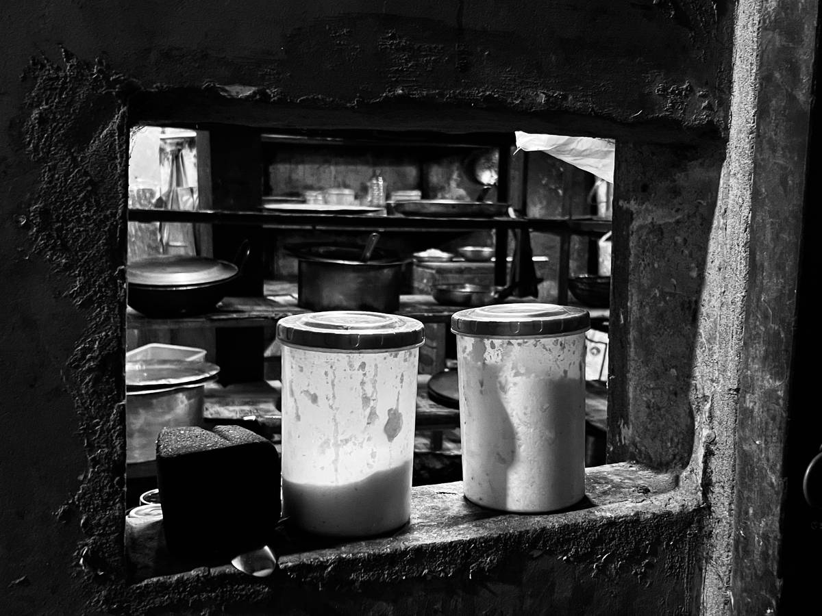 Containers sit in a window, looking into a kitchen.